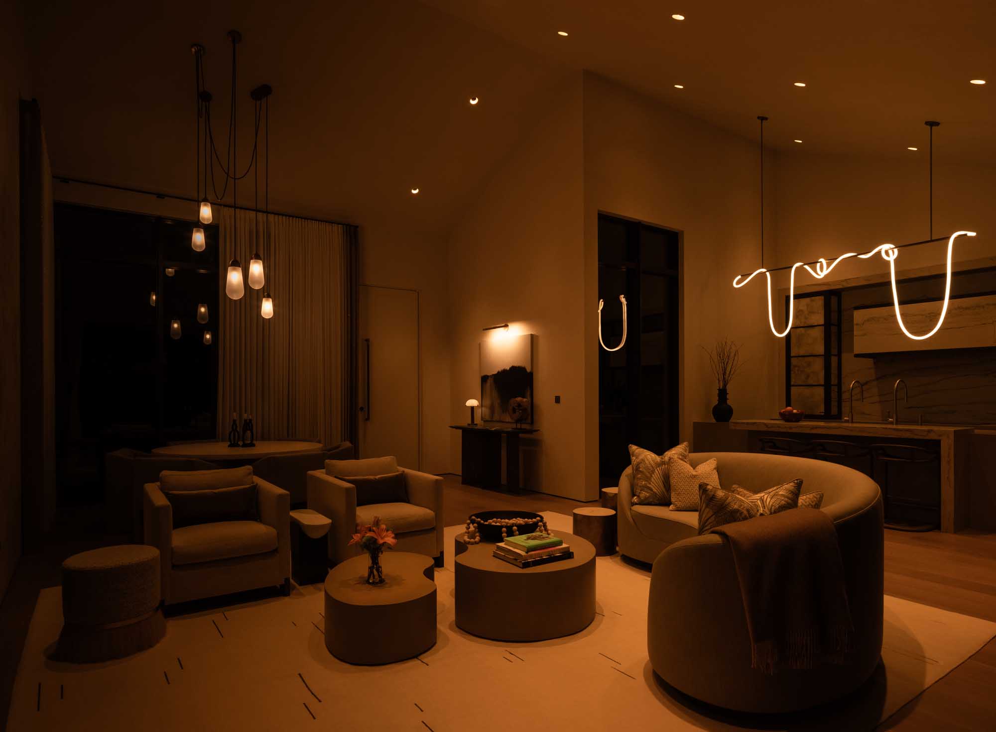 Luxury living room with warm mood lighting featuring a neon sculptural light and pendant lamps