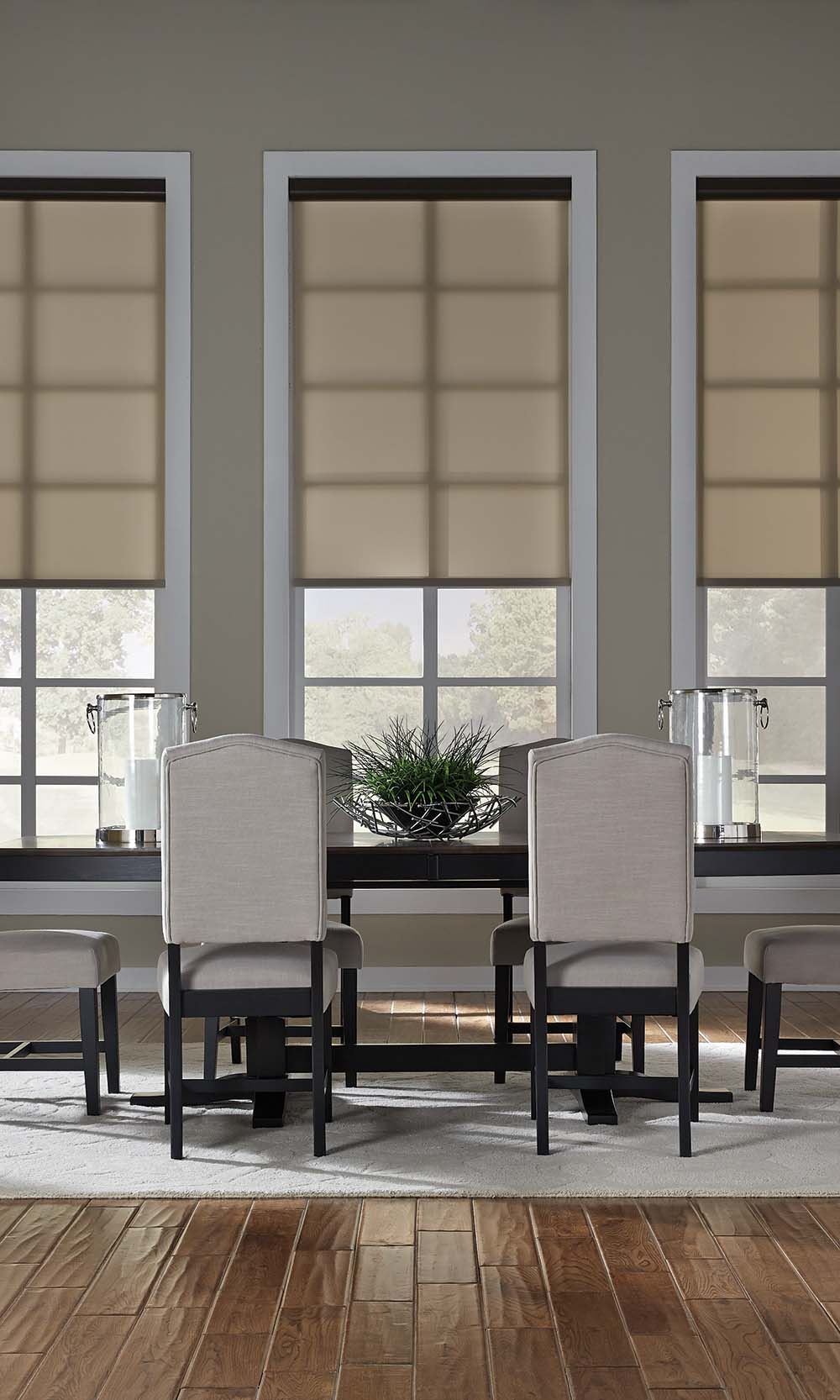 Neutral roller shades lowered halfway over three dining room windows