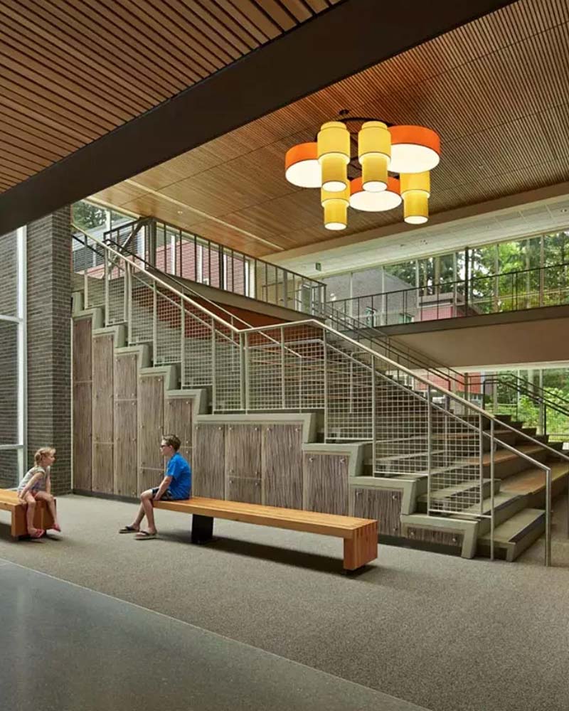 Large multi-tiered drum chandelier with yellow and orange shades in a modern staircase atrium