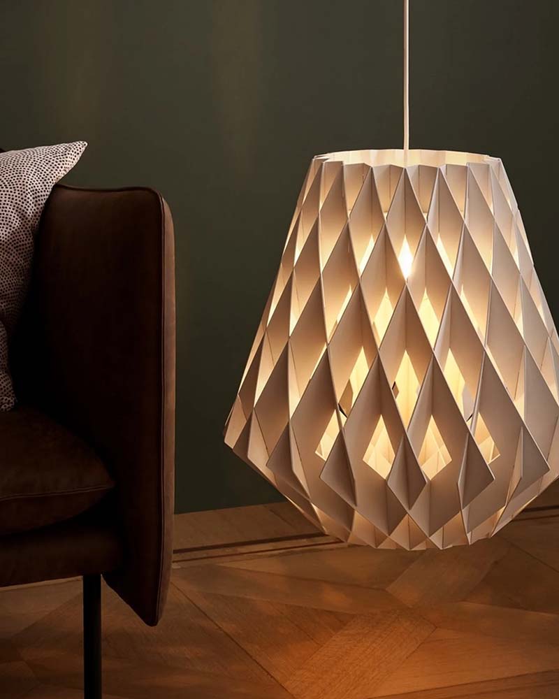 Close up of a white geometric pendant light with a folded paper aesthetic glowing from within