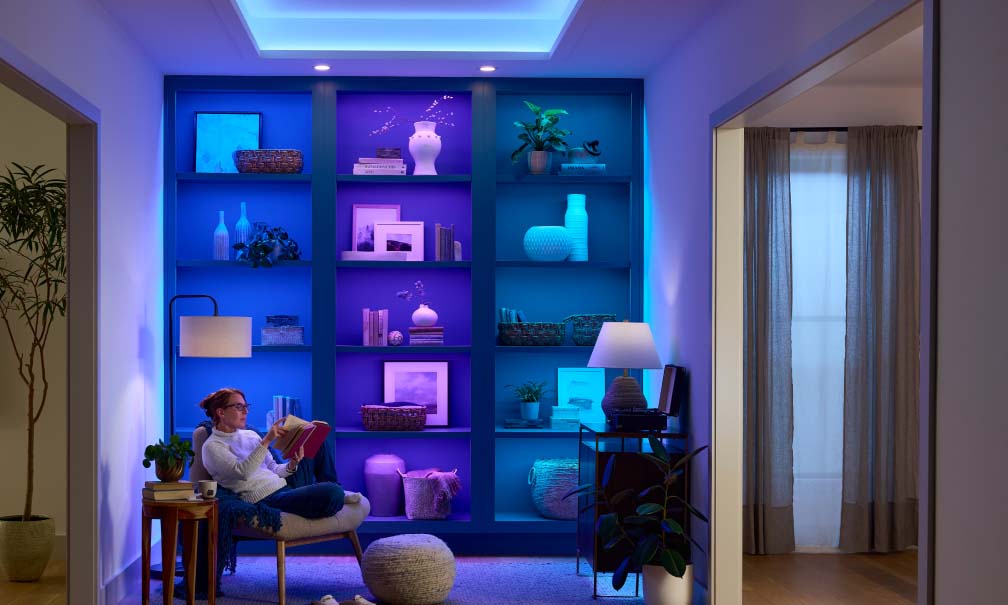 Reading nook featuring a blue backlit bookshelf and warm floor lamps
