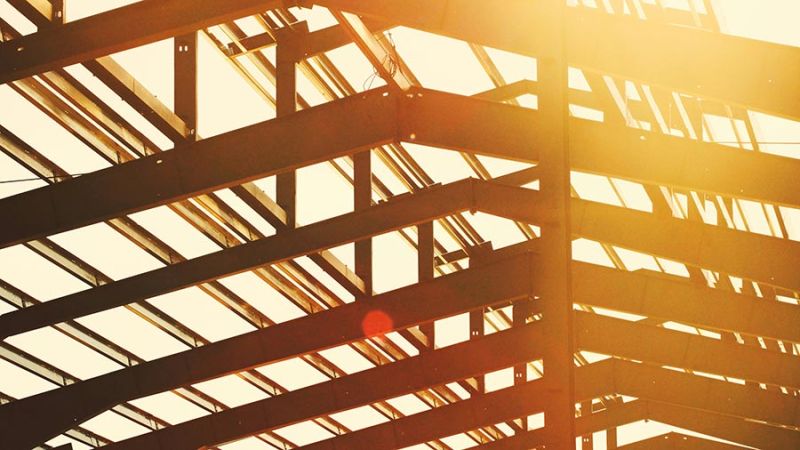 Steel beam framework of a building under construction against a bright sun