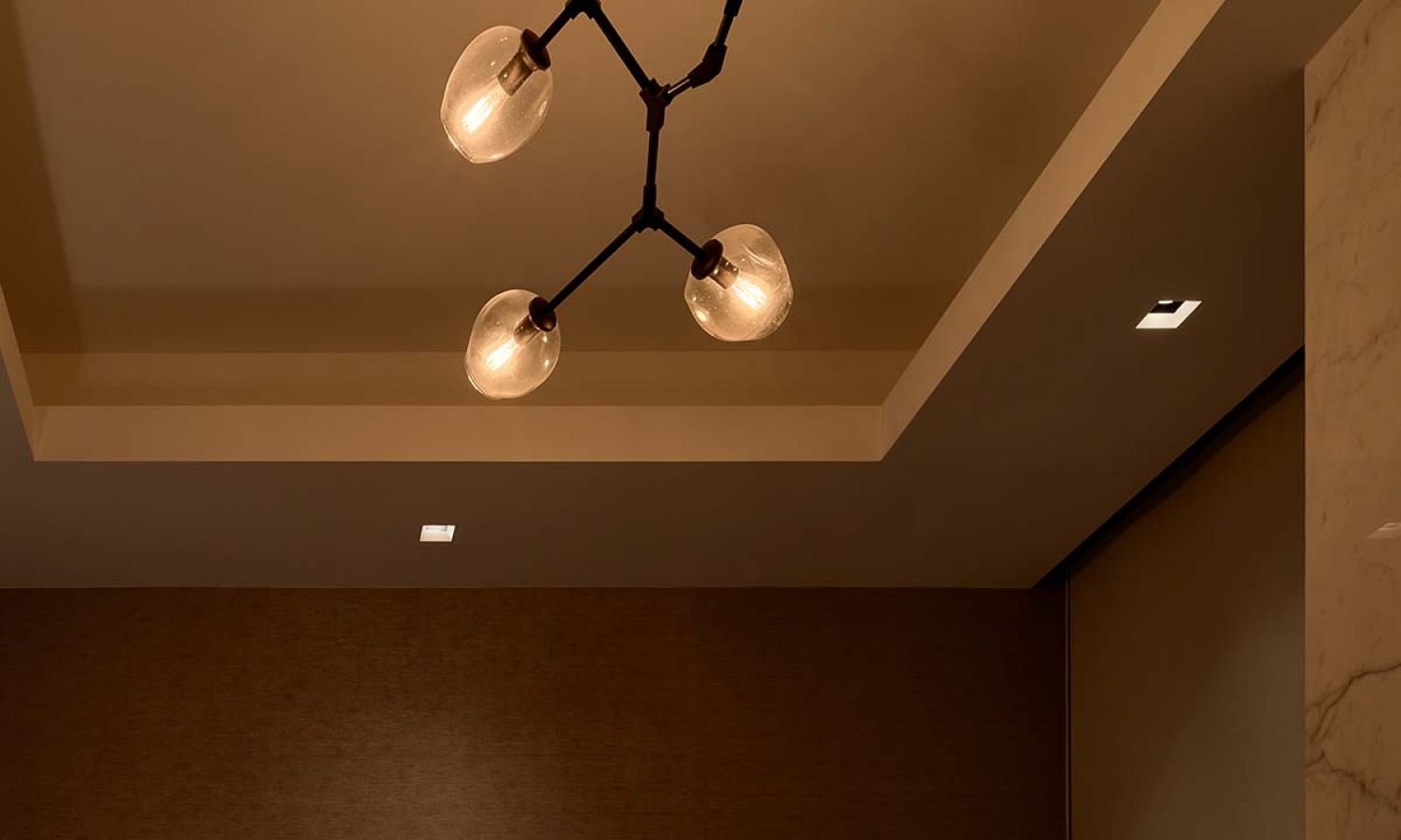 Close up of a modern globe chandelier and recessed ceiling lights with warm dimming effects