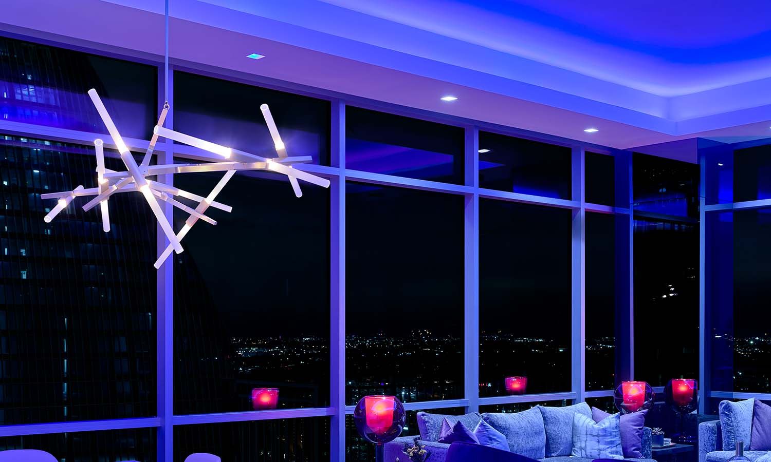 Modern penthouse living room with vibrant blue ambient lighting and a sculptural chandelier